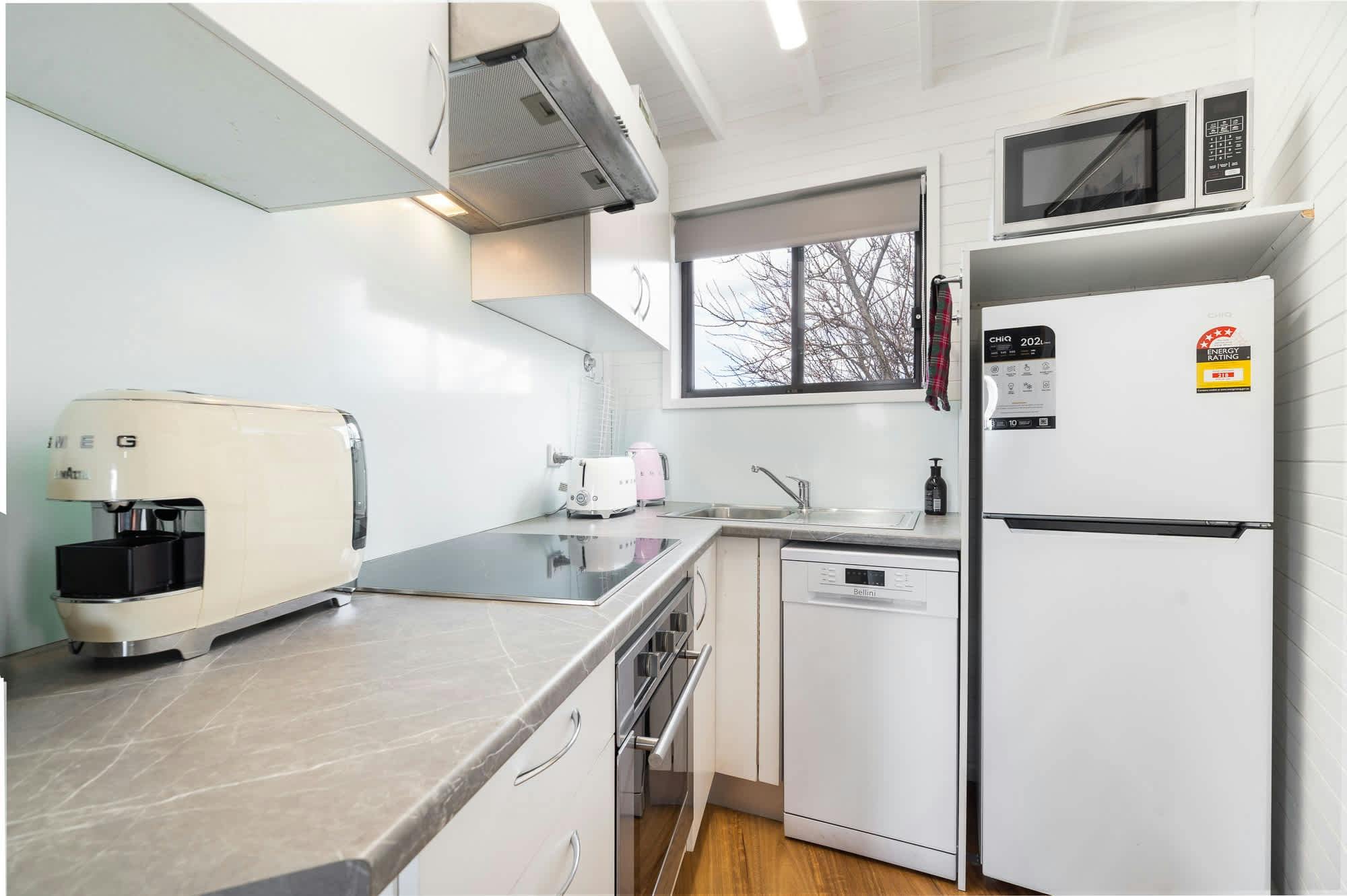 필요한 모든 가전제품과 작은 창문을 갖춘 작지만 효율적인 주방입니다.