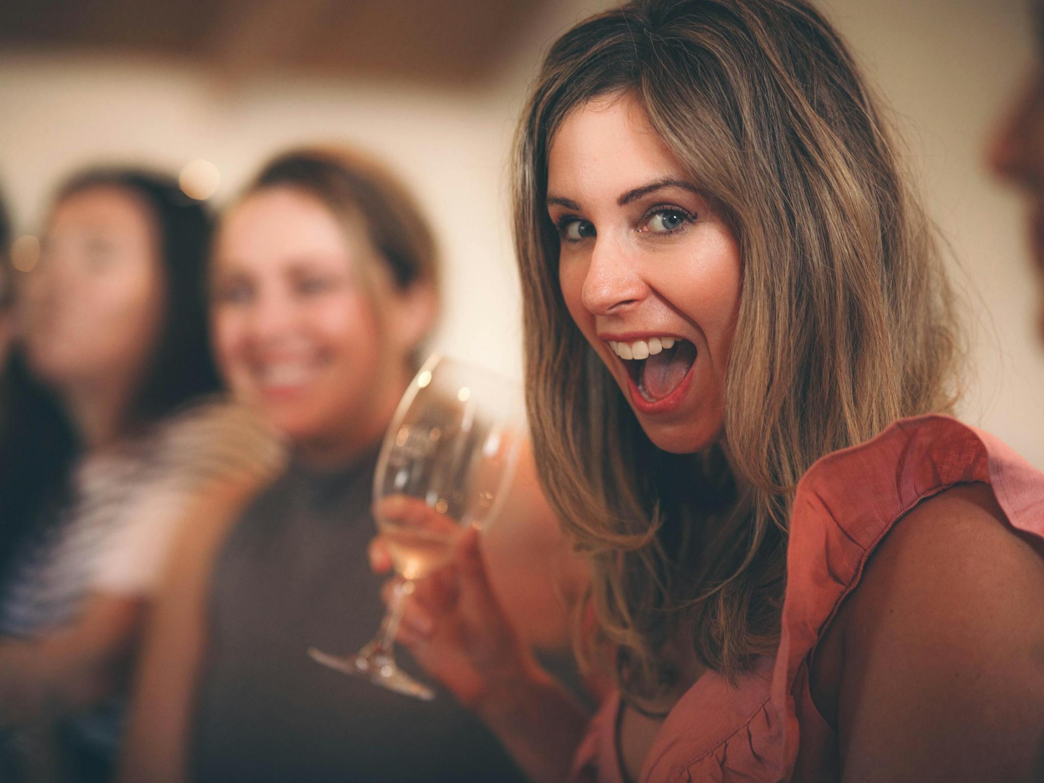 A lady holding a wine glass smiling at the camera
