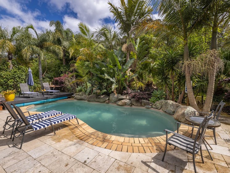The heated pool is surrounded by lush gardens