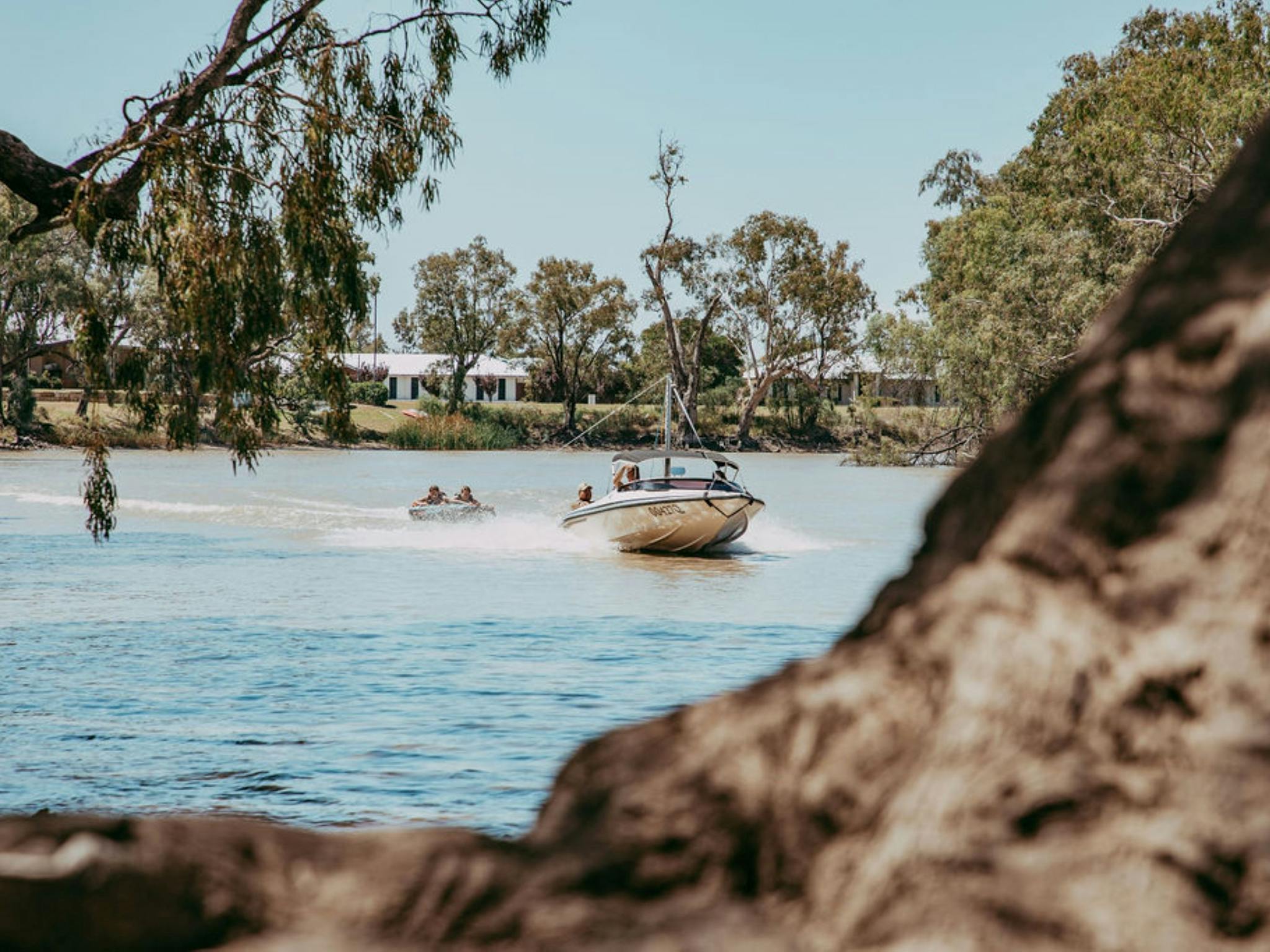 A boat is pulling along kids on a tube in the water at the Goondiwindi Water Park A boat is pulling along kids on a tube in the water at the Goondiwindi Water Park