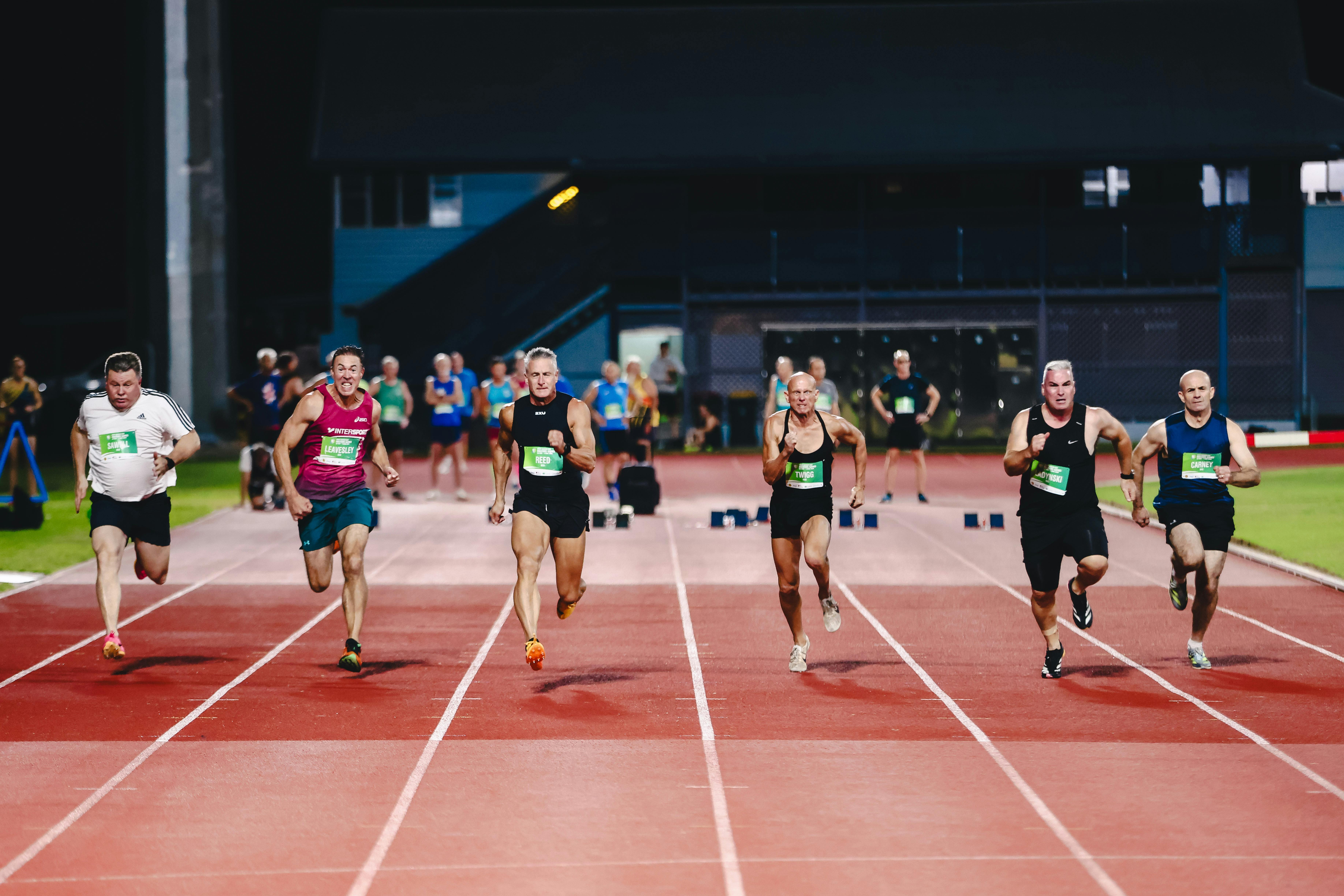 Several athletes sprinting on a track during a night race