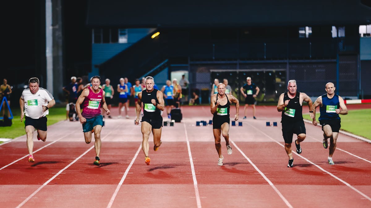 Several athletes sprinting on a track during a night race