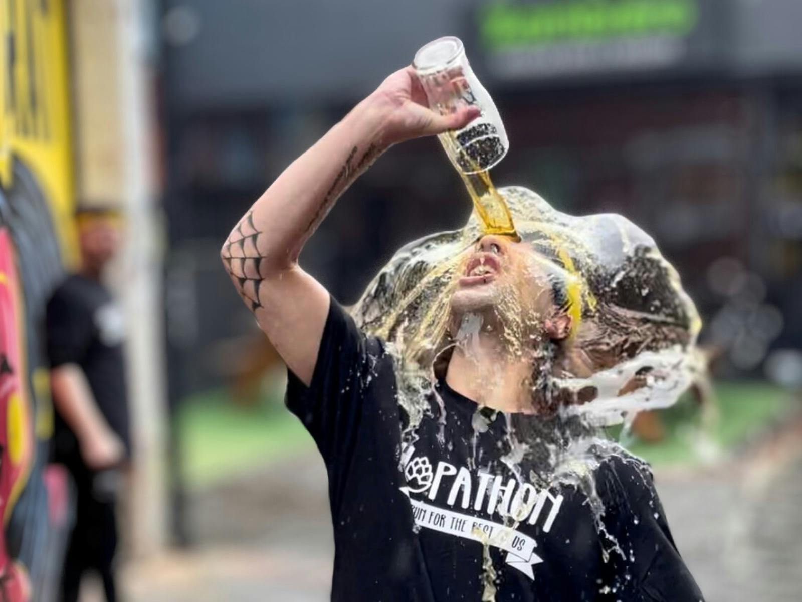Man splashing his face with a pint of beer