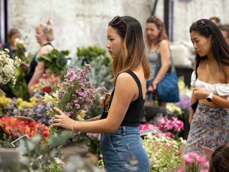 A woman selects a brightly coloured bunch of flowers at a florist