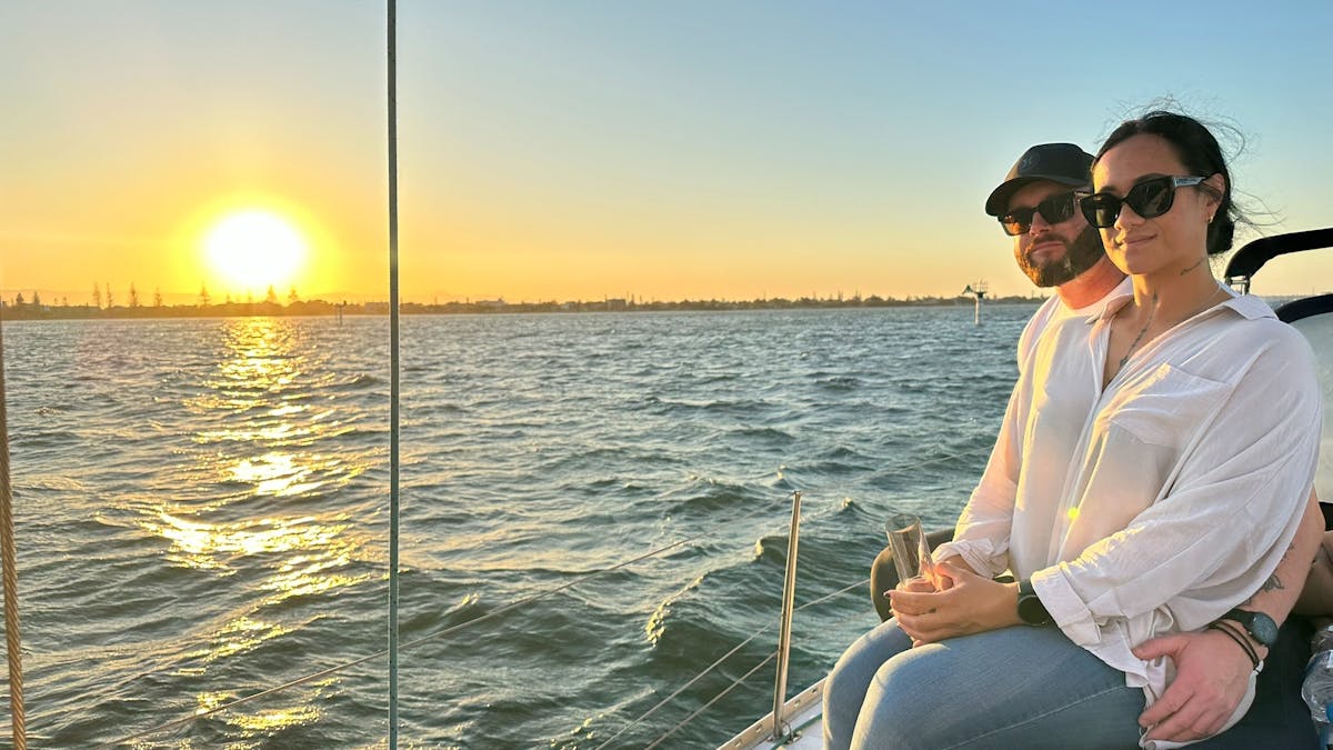 Couple sitting on deck Sun Sailing yacht watching the sun set on the Gold Coast Broadwater.