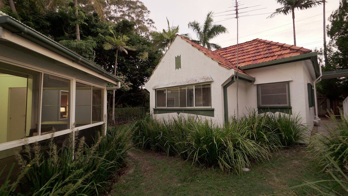 Older cottage with palm trees in the background.