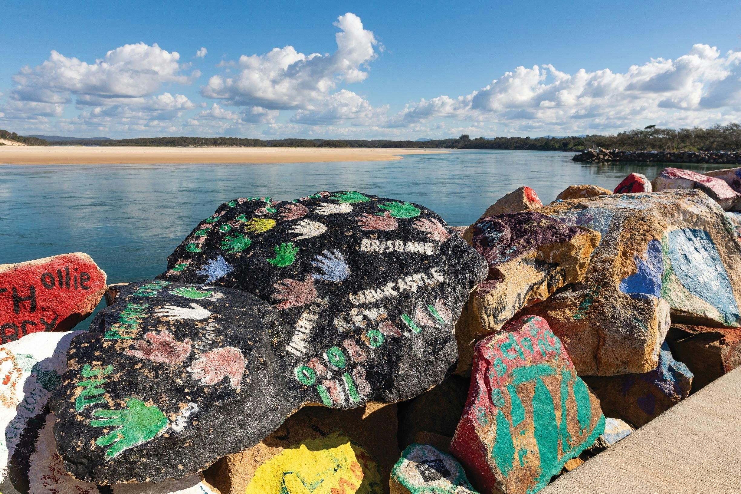 Looking up the Nambucca River esturary, colourful painted rocks in the foreground