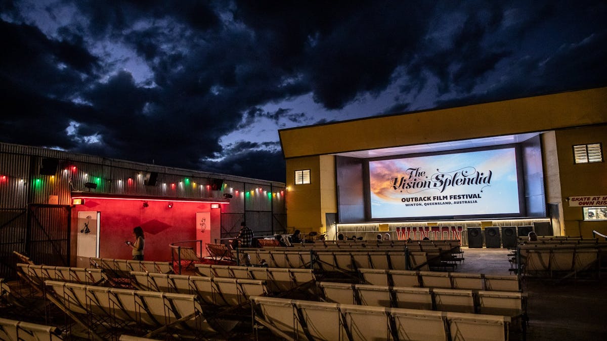 Open-air cinema at Vision Splendid Film Festival under a cloudy night sky, seats awaiting guests.