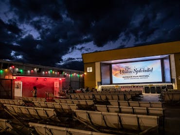 Open-air cinema at Vision Splendid Film Festival under a cloudy night sky, seats awaiting guests.