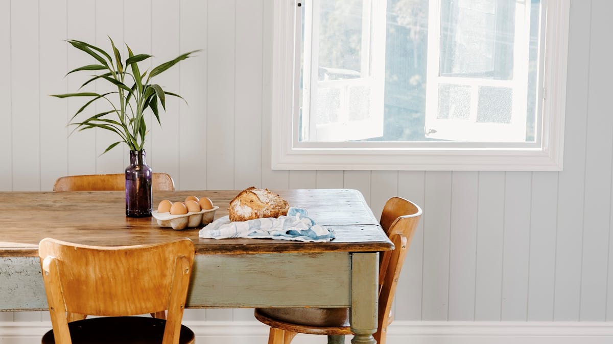 Traditional vintage kitchen table, with fresh eggs & sourdough bread, hopscotch window behind