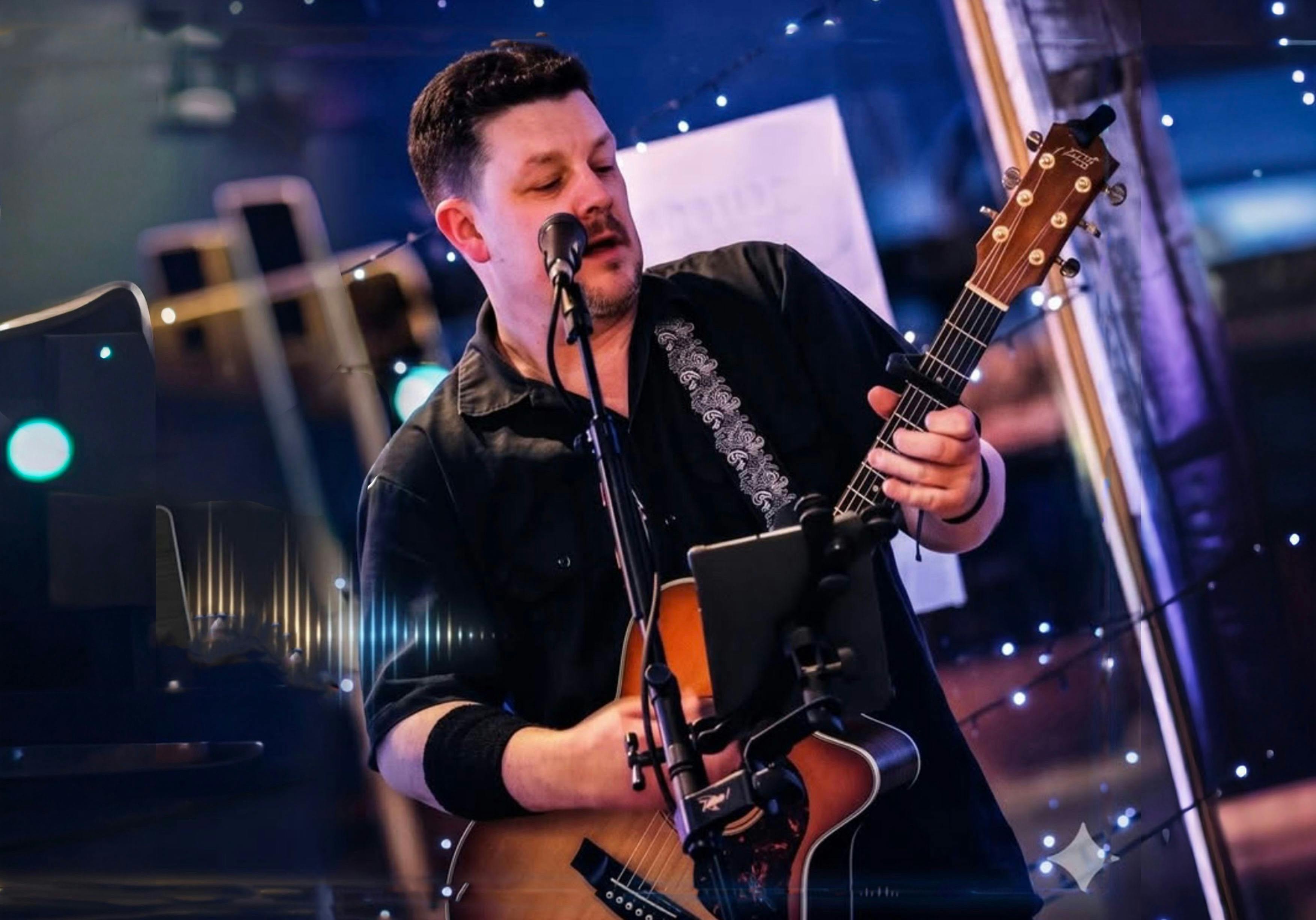 Man in black shirt  singing with acoustic guitar