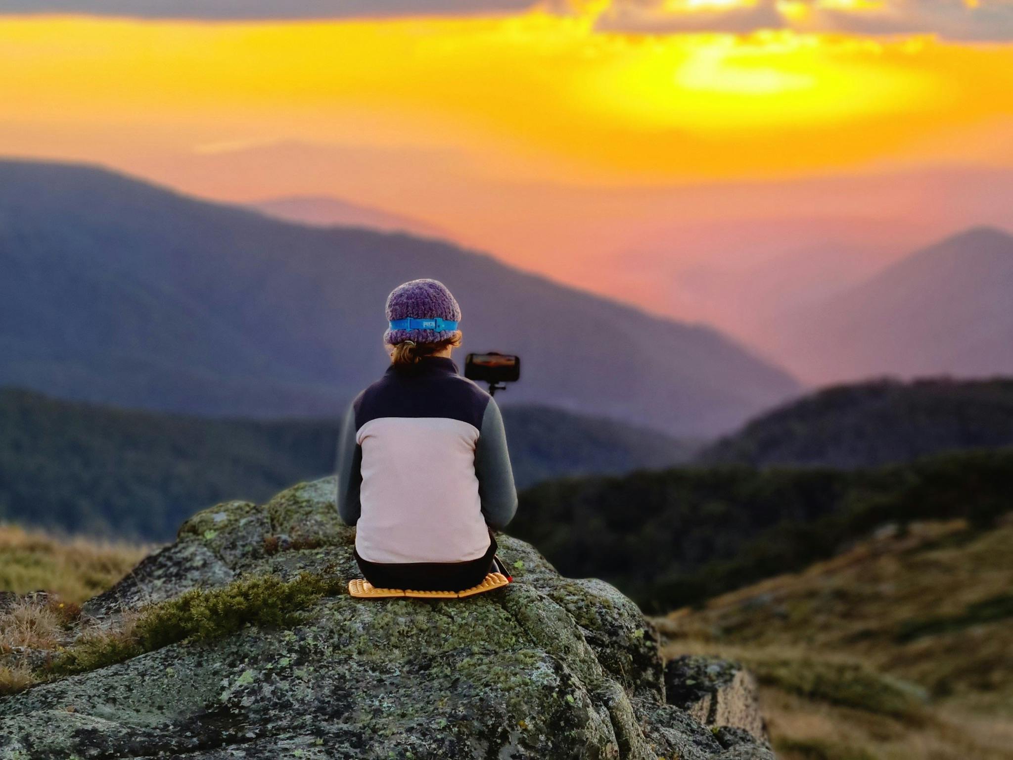 A young hiker capturing sunset from Mt Stirling on her camera.