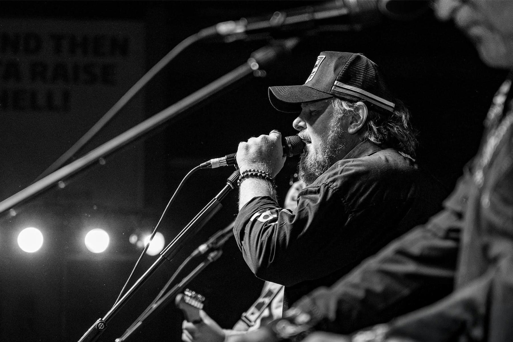 Black and White image of Ross Webb Singing into a microphone on stage