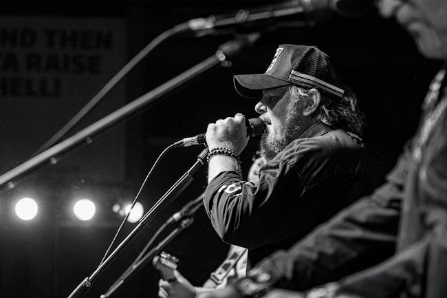 Black and White image of Ross Webb Singing into a microphone on stage