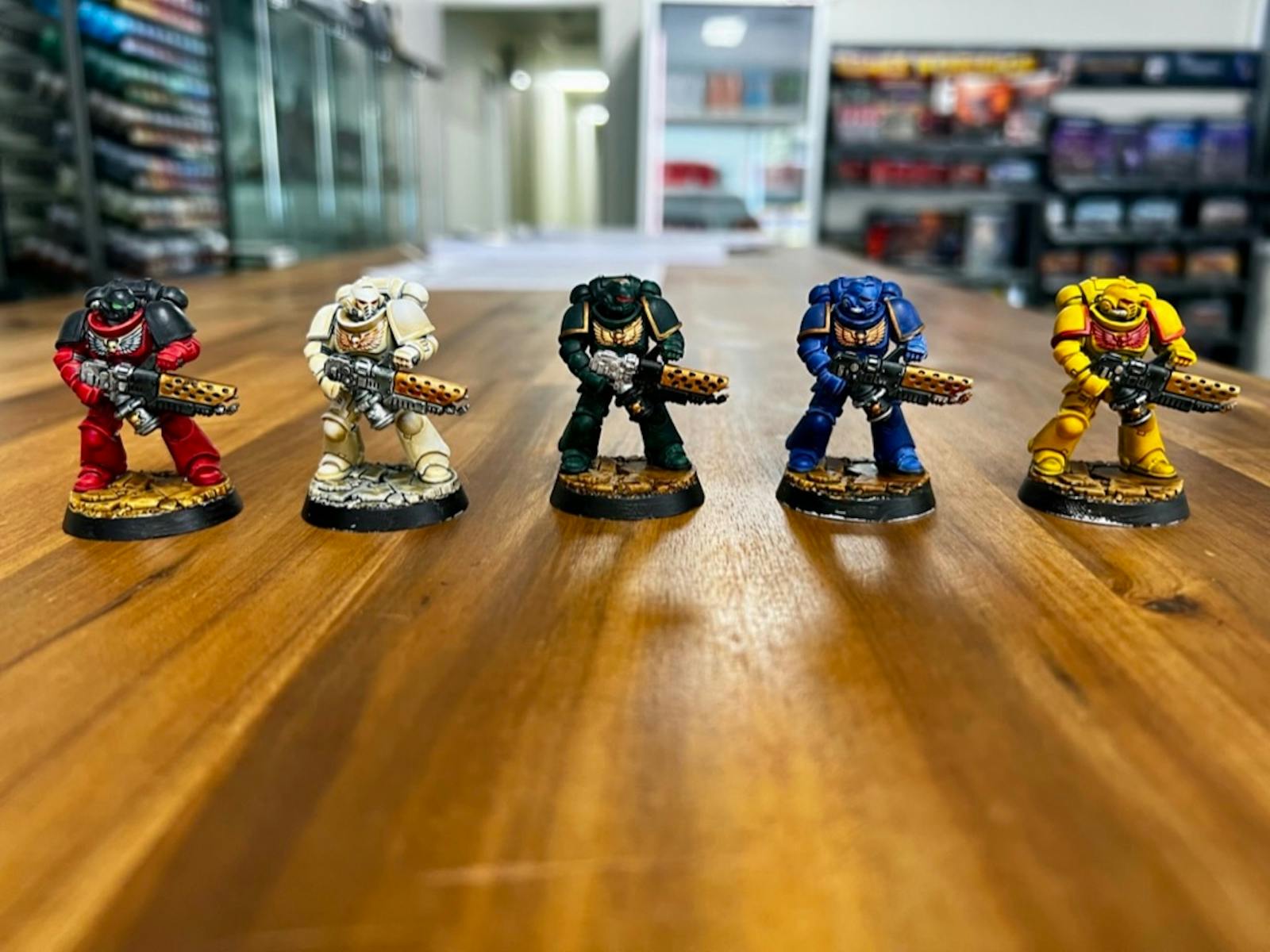 Five painted Warhammer miniatures displayed on a wooden table.
