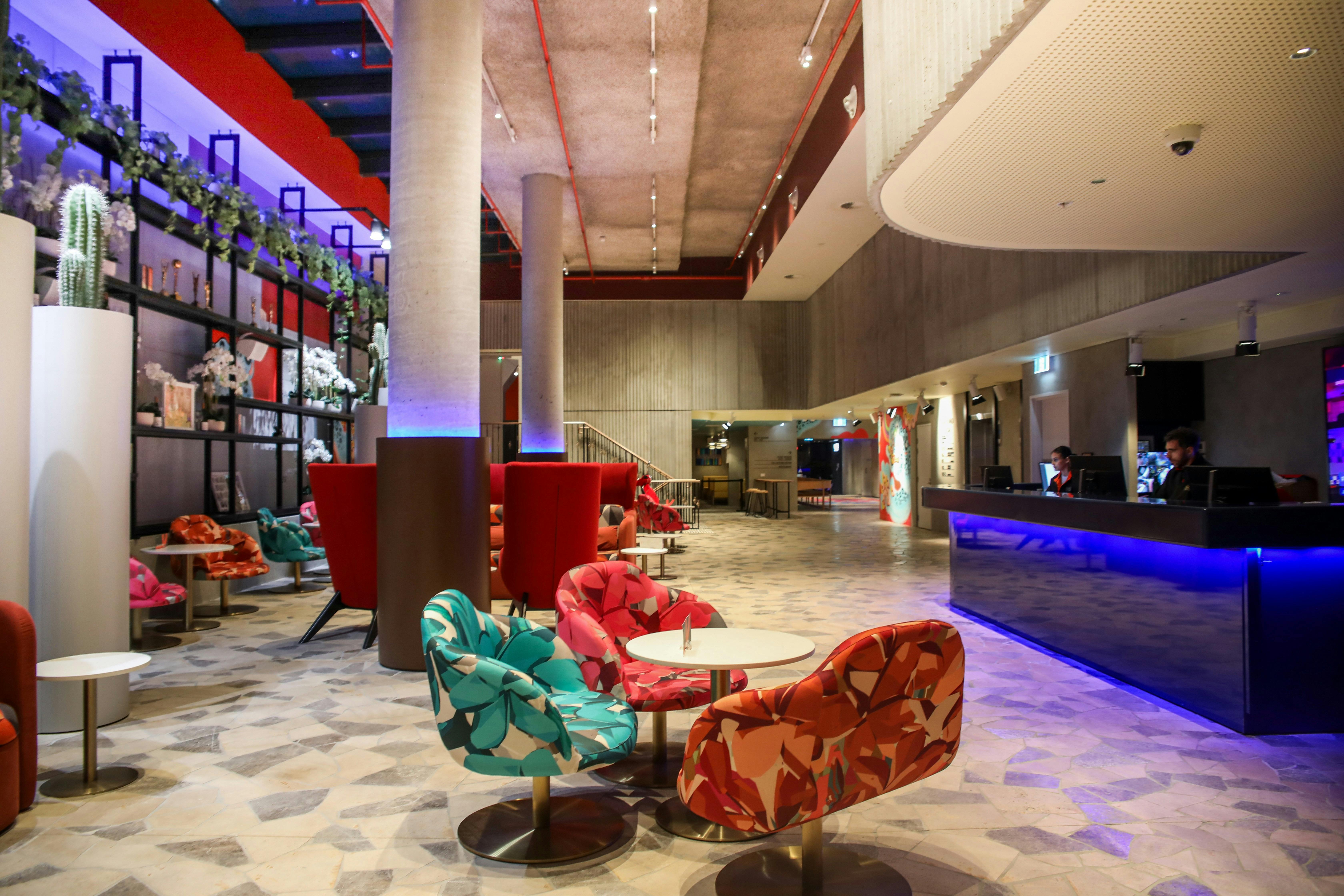 Photo of lobby area, flagstone tile flooring with blue desk and abstract colour furniture.