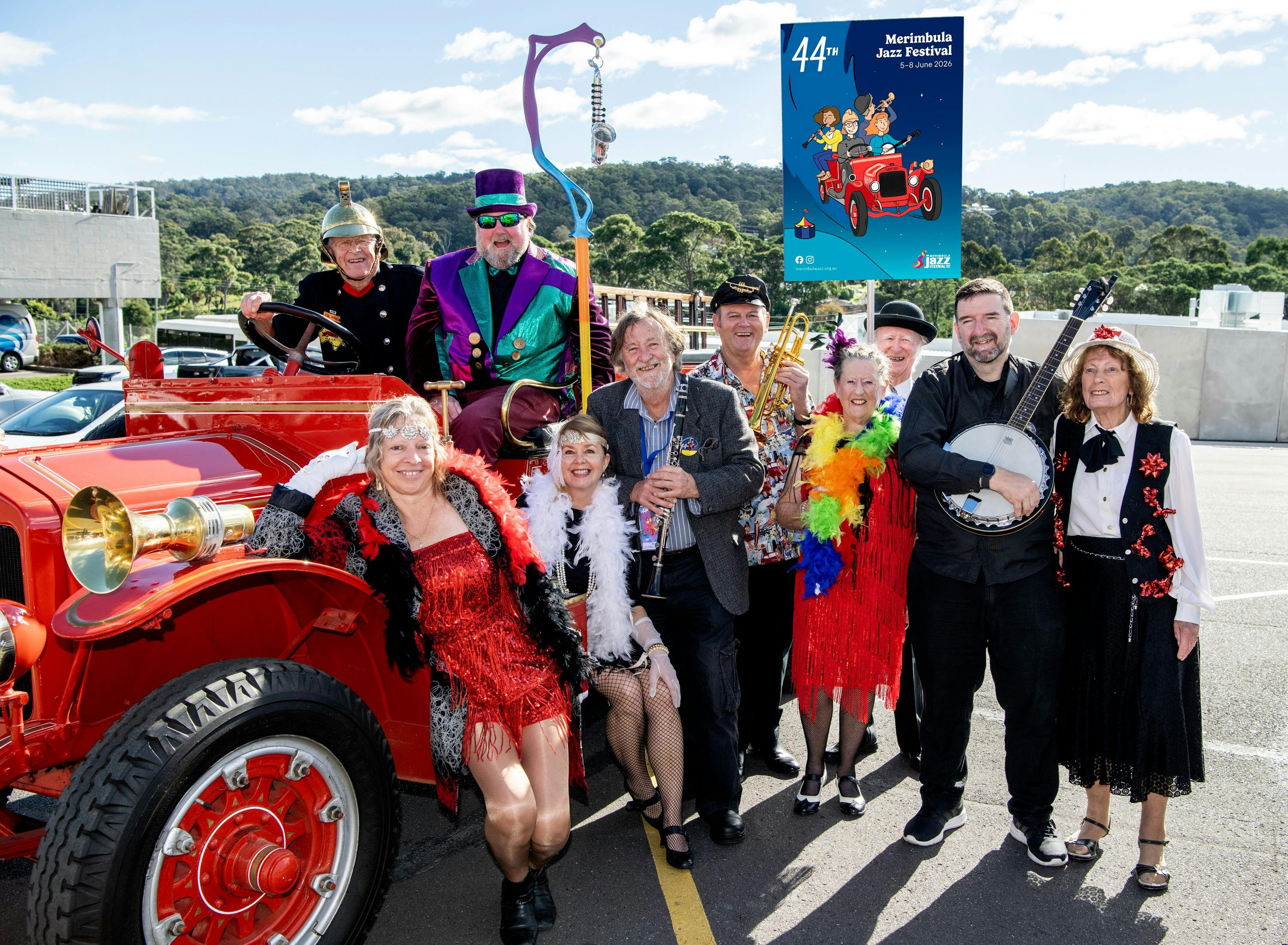 Vintage fire truck with dancers and musicians standing next to it.