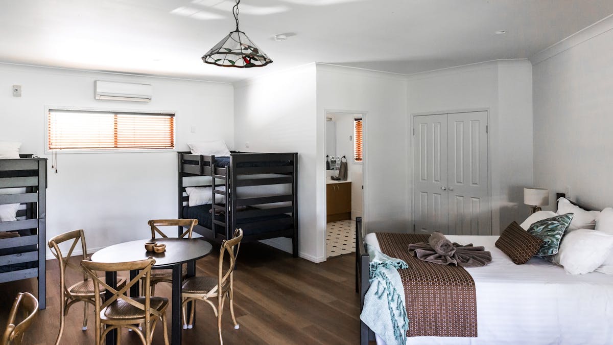 Bunk bed in corner. Queen bed. Circle table with 4 chairs around. Pendant light in middle of room