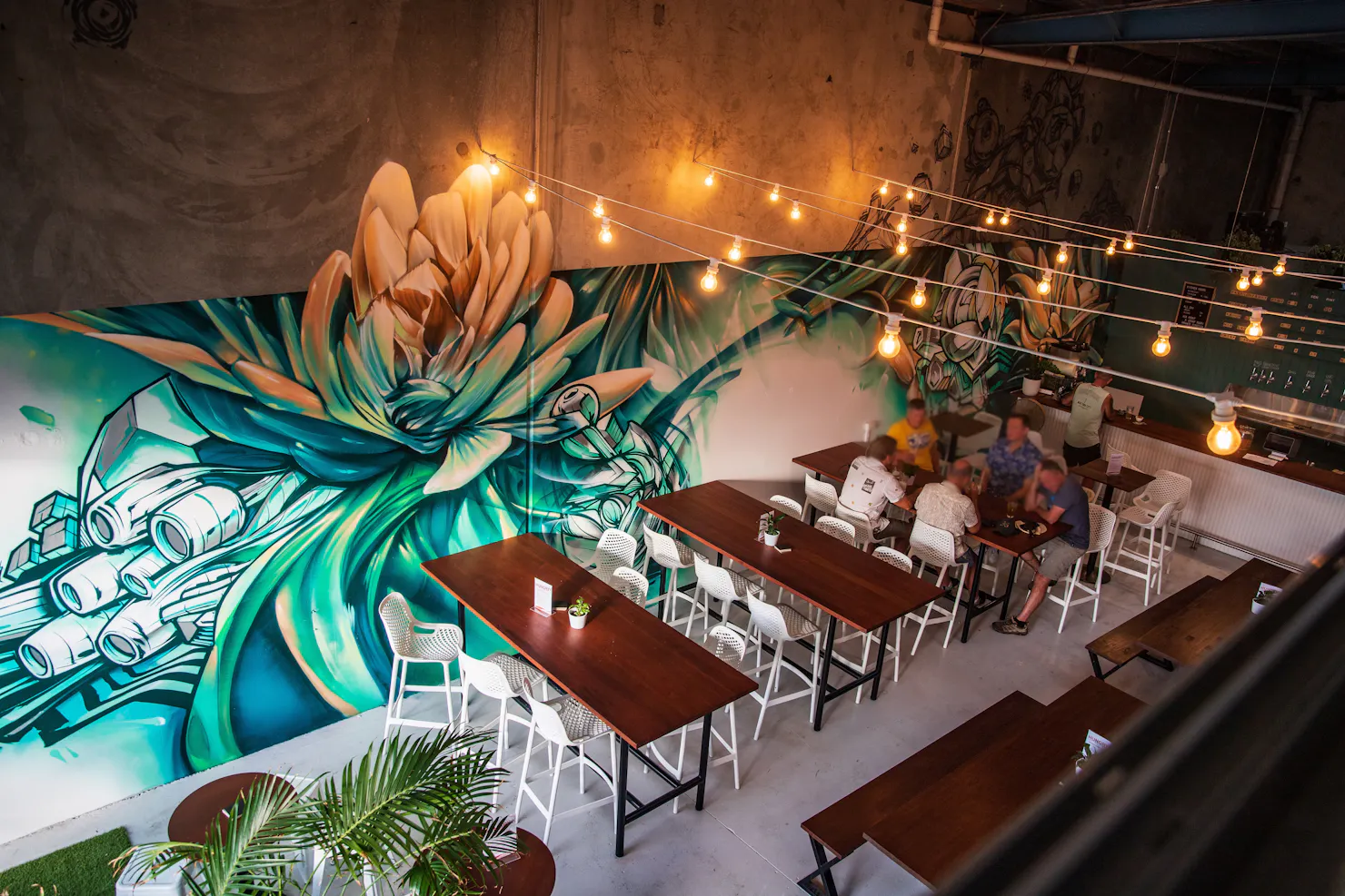 Young Giants Brewing taproom glows with @Sofles’ vibrant mural, where art meets craft beer.