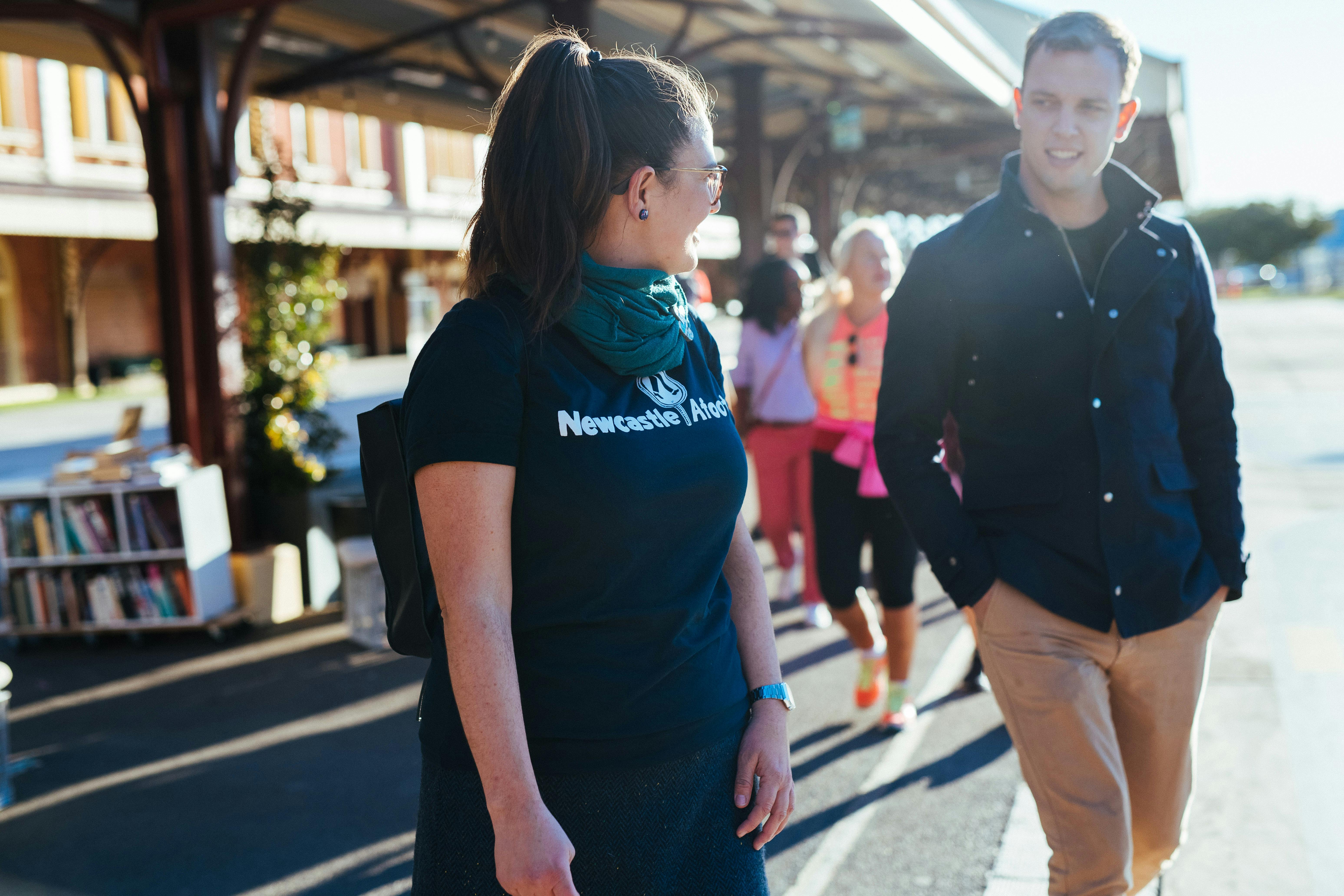 A Newcastle Afoot guide talks with a guest in front of a market place