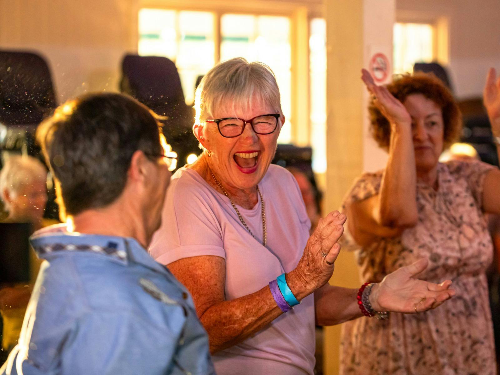 Three woman Trail Travellers enjoying an event while smiling, laughing, and clapping their hands