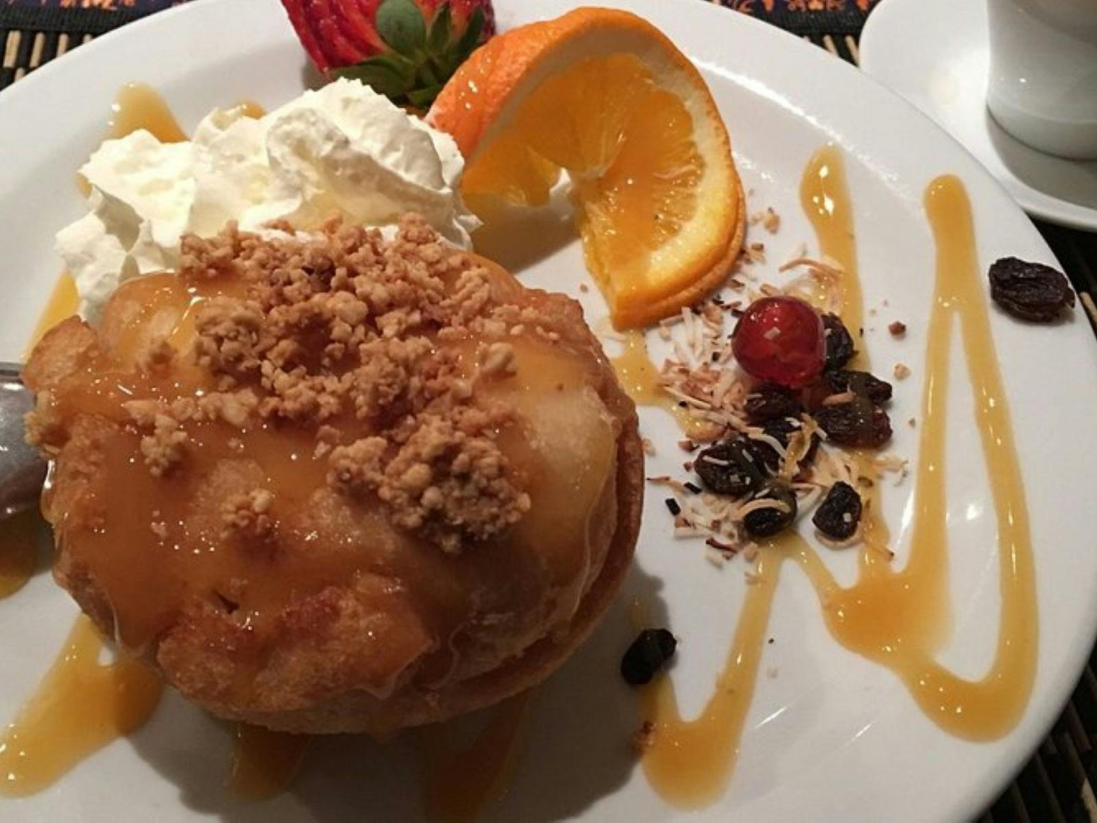 Image of a dessert plate with a large round fried ball with ice cream and orange syrup