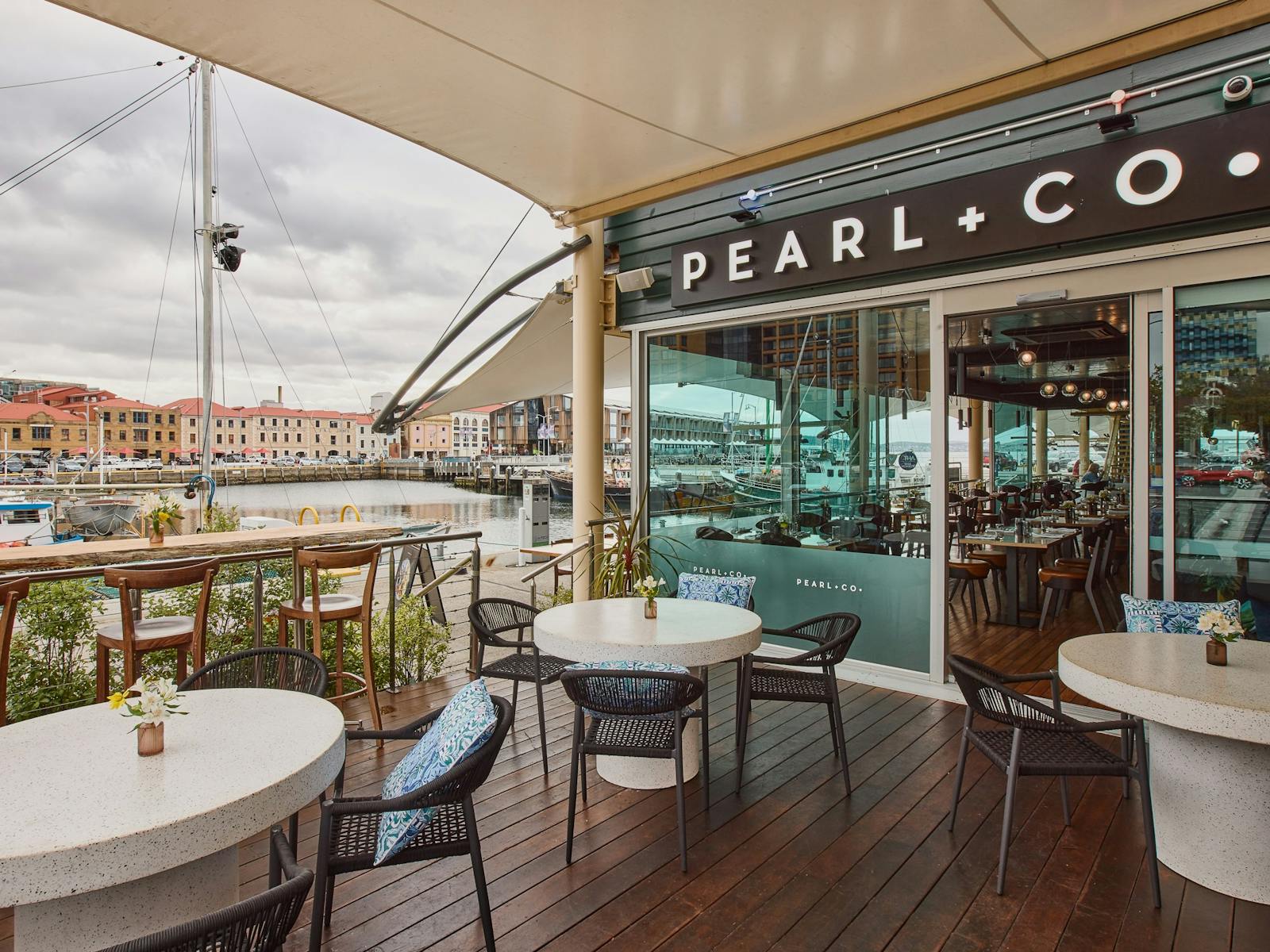 Pearl restaurant's outdoor deck offering round tables and seating, overlooking Victoria Dock
