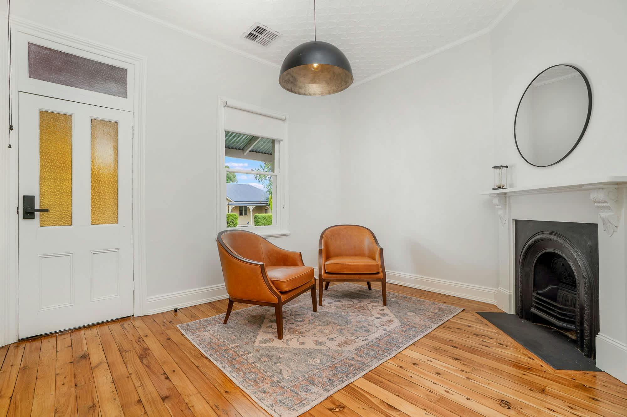 2 armchairs with a rug, fire place and mirror right at the entrance of Elegant Edward