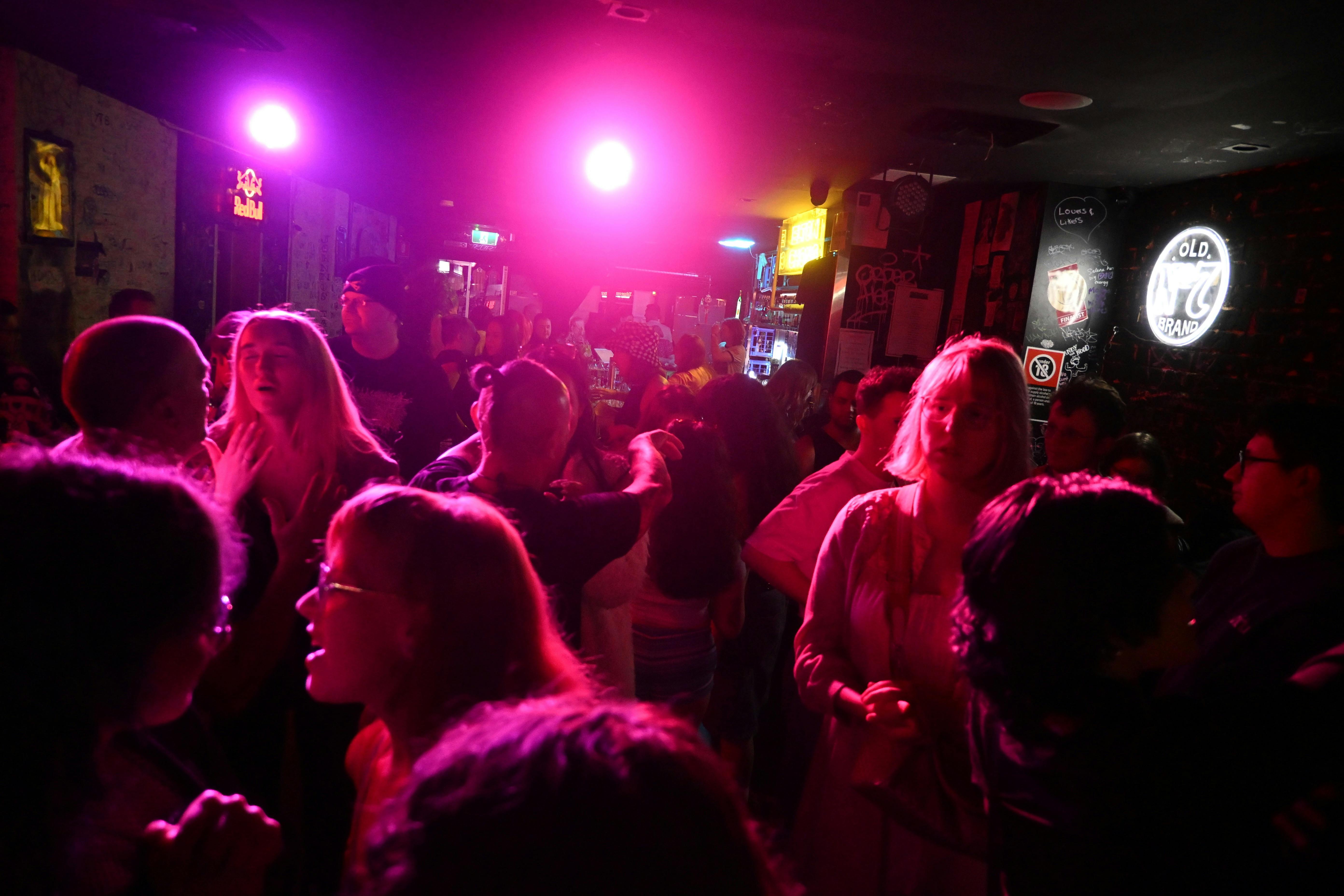 A diverse crowd of people dances under glowing coloured lights