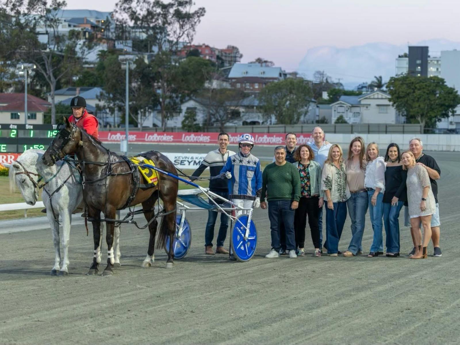 Race sponsors celebrate with winning horse and driver.