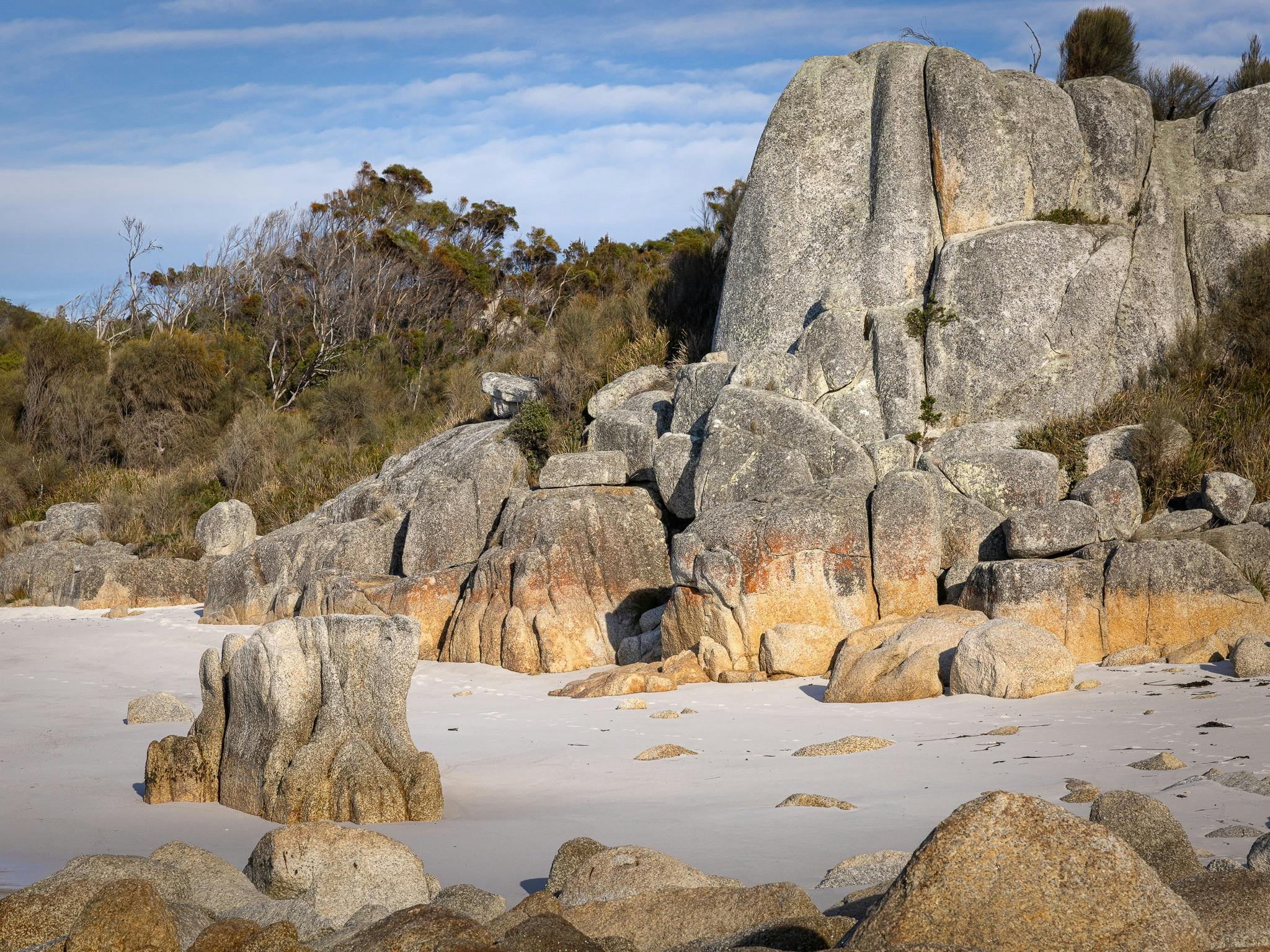 pristine beach line by coastal lichen coloured rocks
