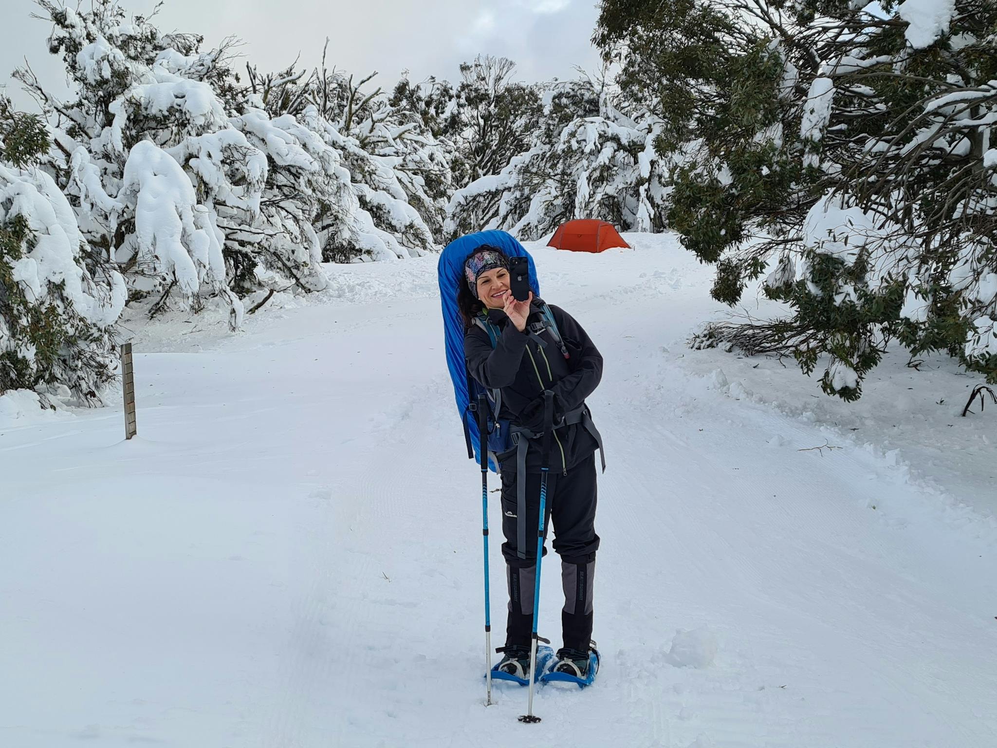 A hiker snapping photos of the snow covered landscape.