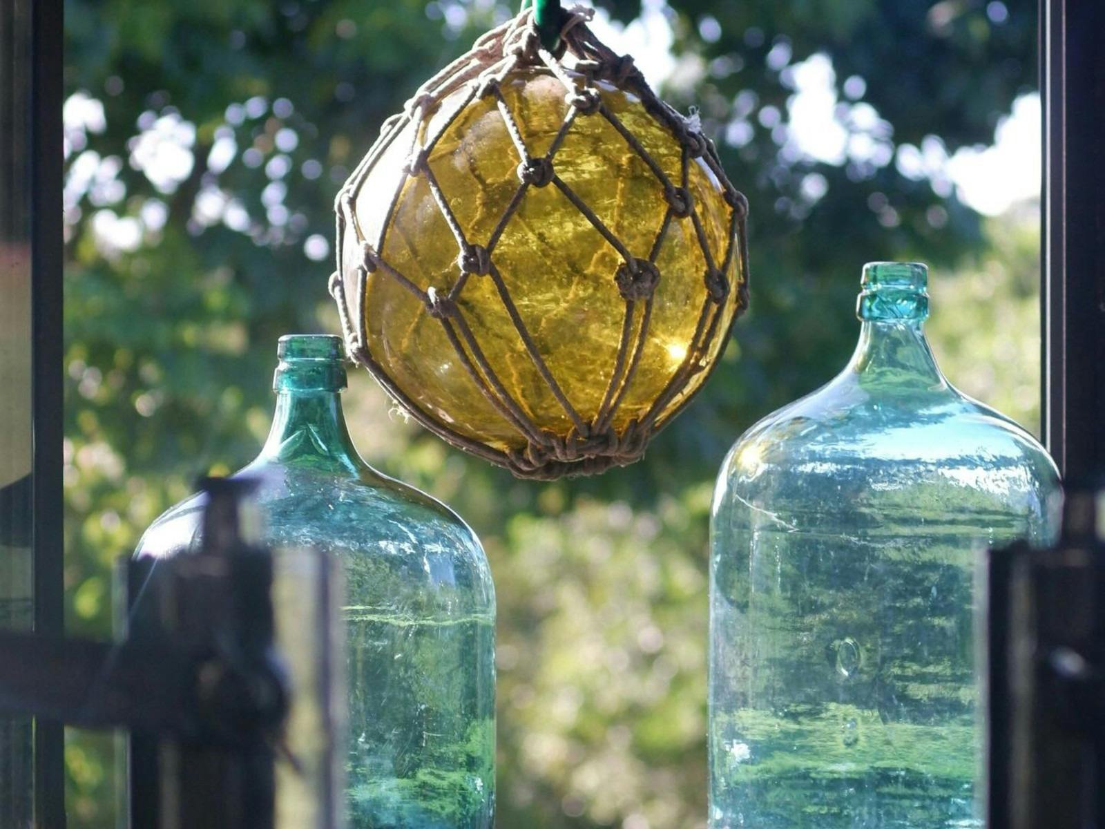 one yellow glass fising float hanging between two glass bottles