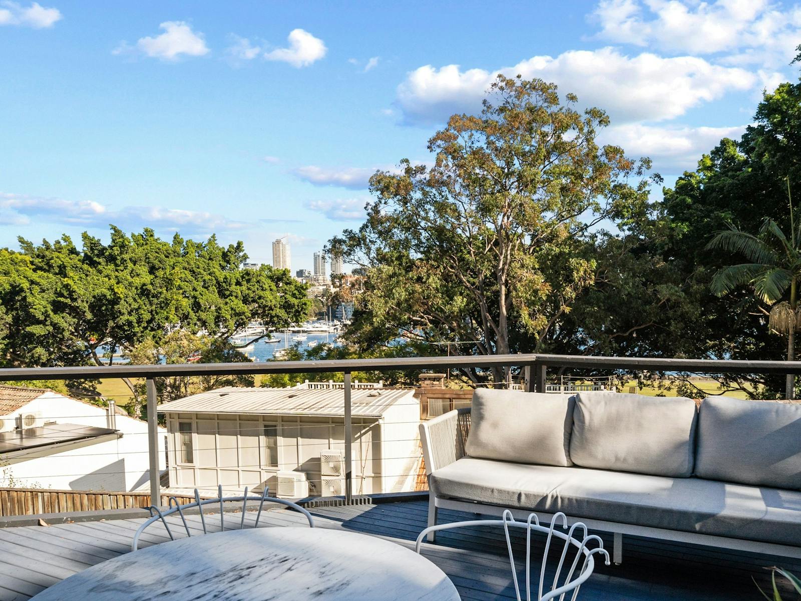 Terrace with sofa and table overlooking trees and the harbor.