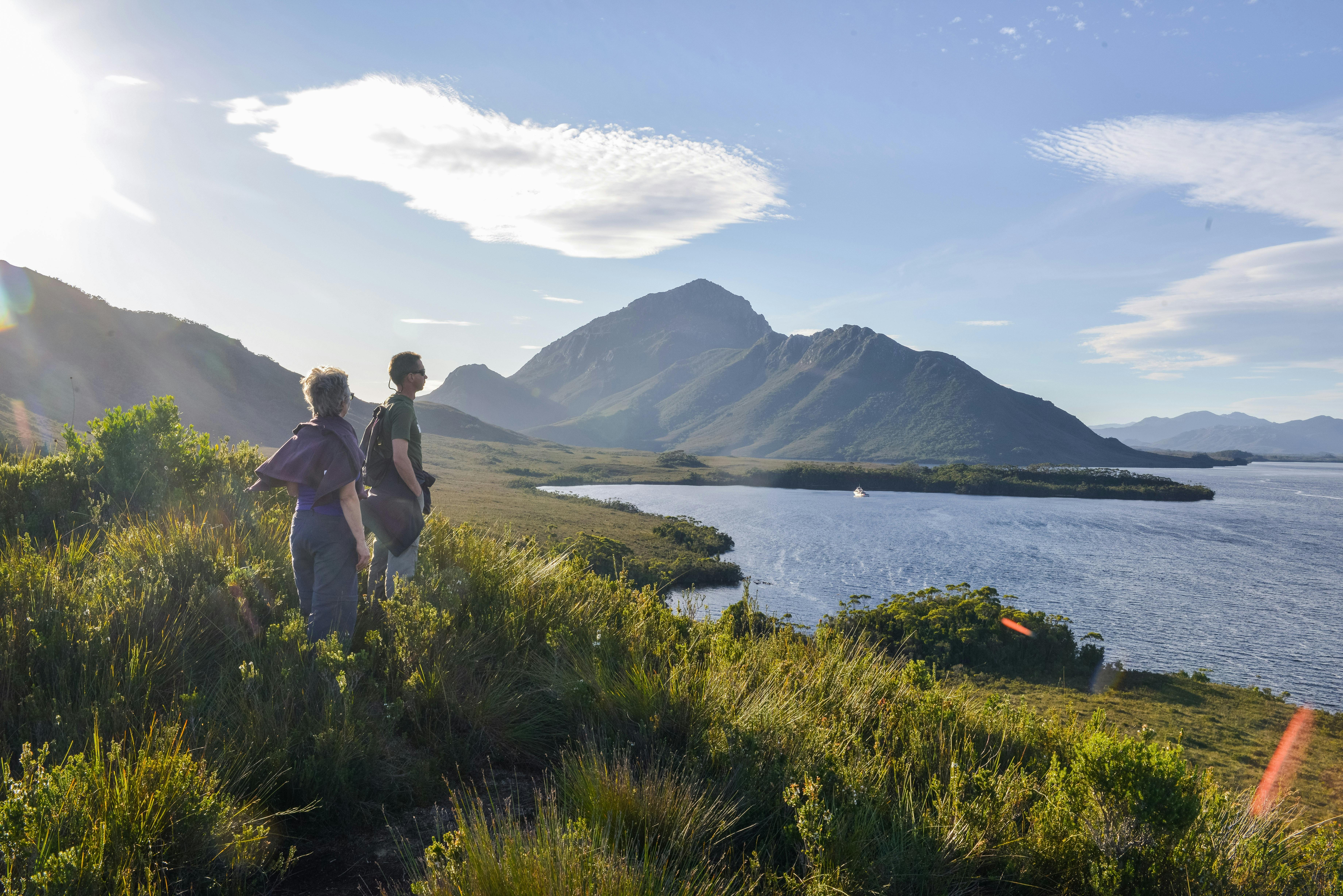2 people on a walk looking over Port Davey and the vessel.