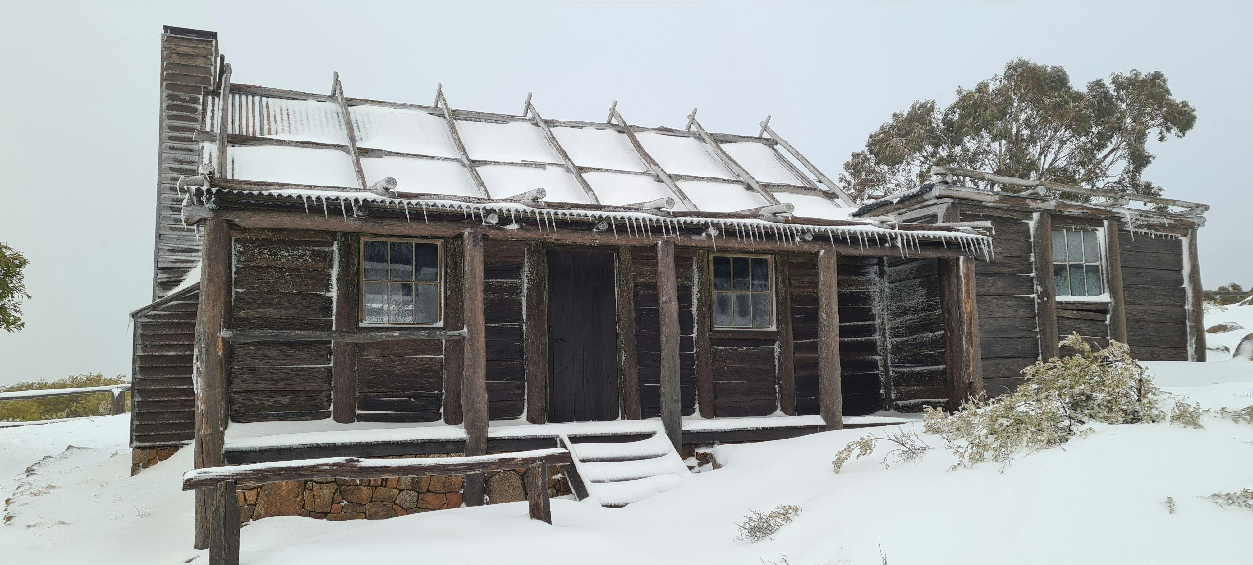 Craig's Hut covered in snow with icicles hanging from the roof