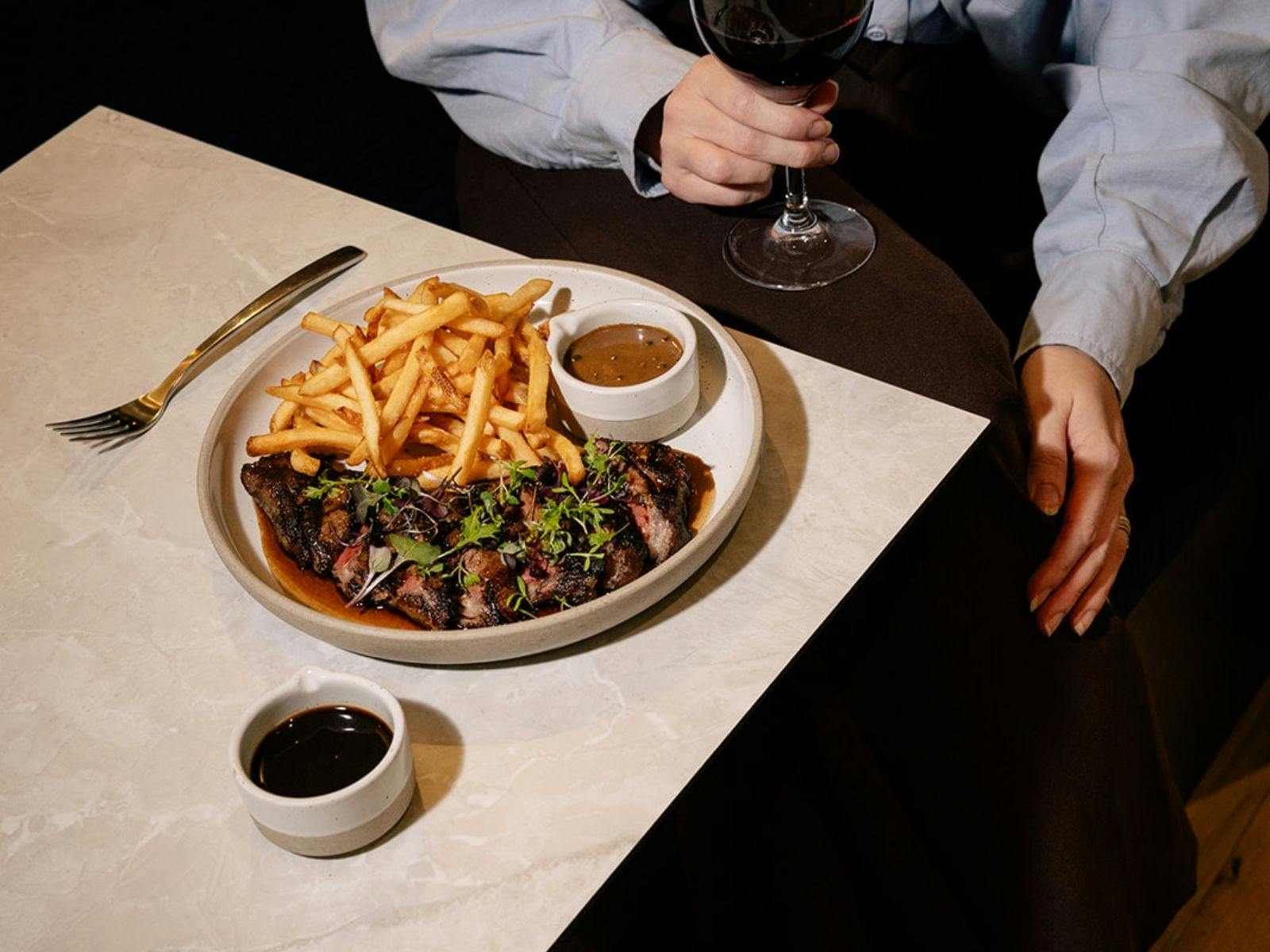 Steak Frites on a table with a glass of red wine