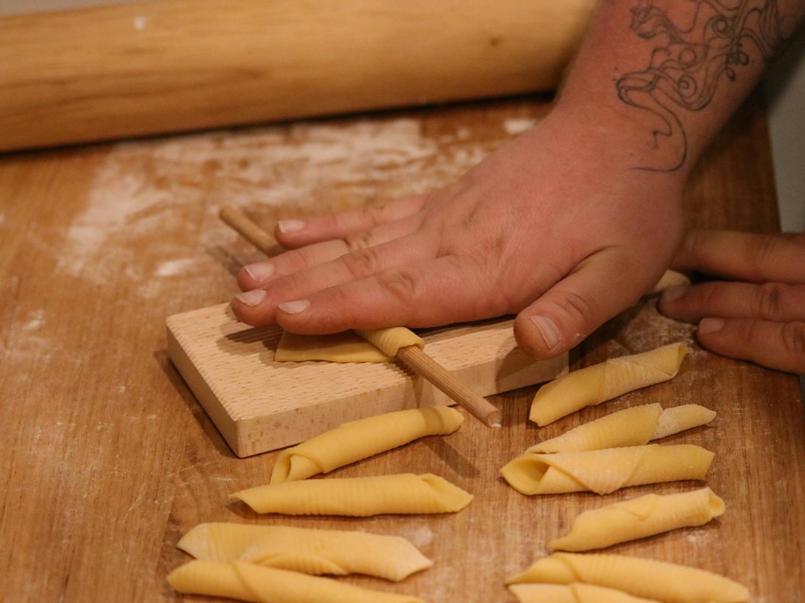 A hand rolling Garganelli Pasta on a gnocchi Board