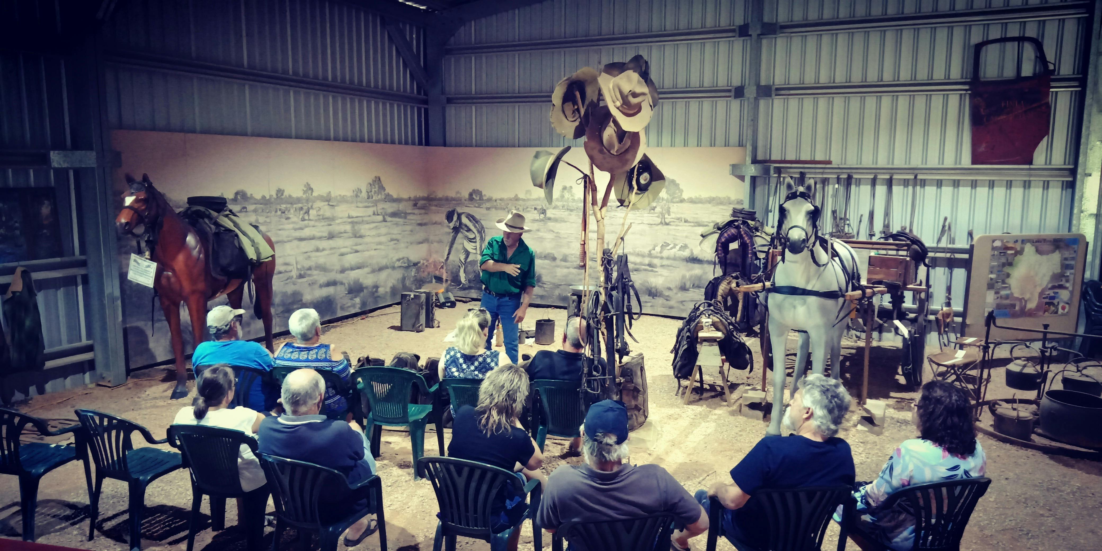 Ex-drover explaining life of a drover to the group at the packhorse night camp display area.