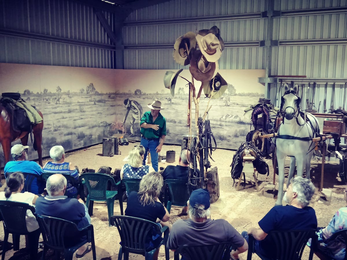 Ex-drover explaining life of a drover to the group at the packhorse night camp display area. Ex-drover explaining life of a drover to the group at the packhorse night camp display area.