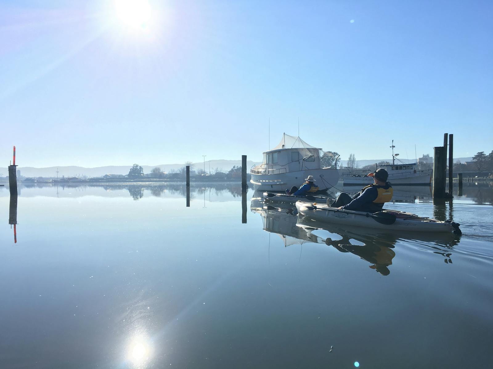 2 people in kayaks paddle on calm reflective water on the Tamar River