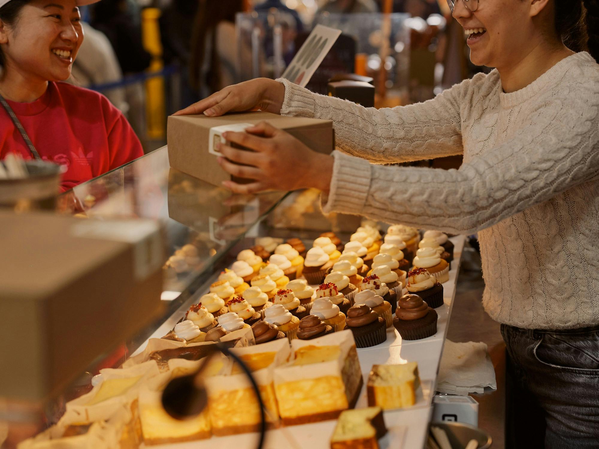 Customer purchasing cupcakes and cheesecakes from a South Melbourne Market bakery.