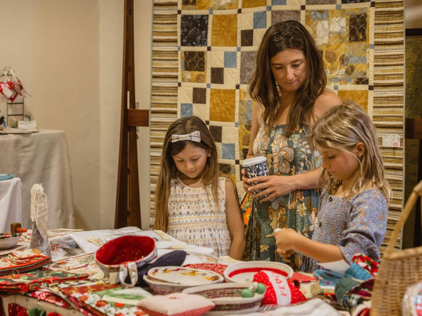 A woman and children explore the unique products on display at the Pinjarra Patchworks and Quilters