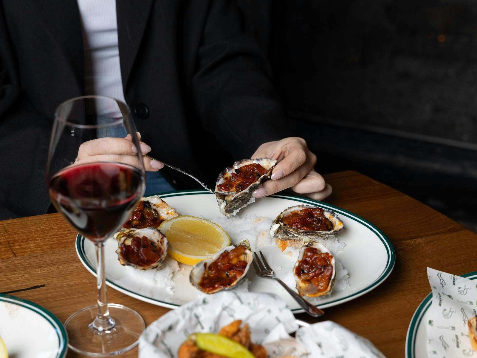 glass of red wine, oysters being eaten with a fork