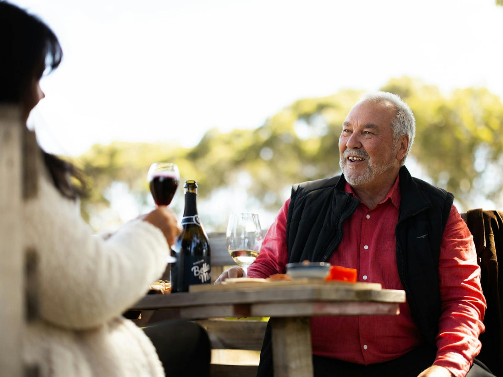 Image of two people enjoying a glass of red wine and food