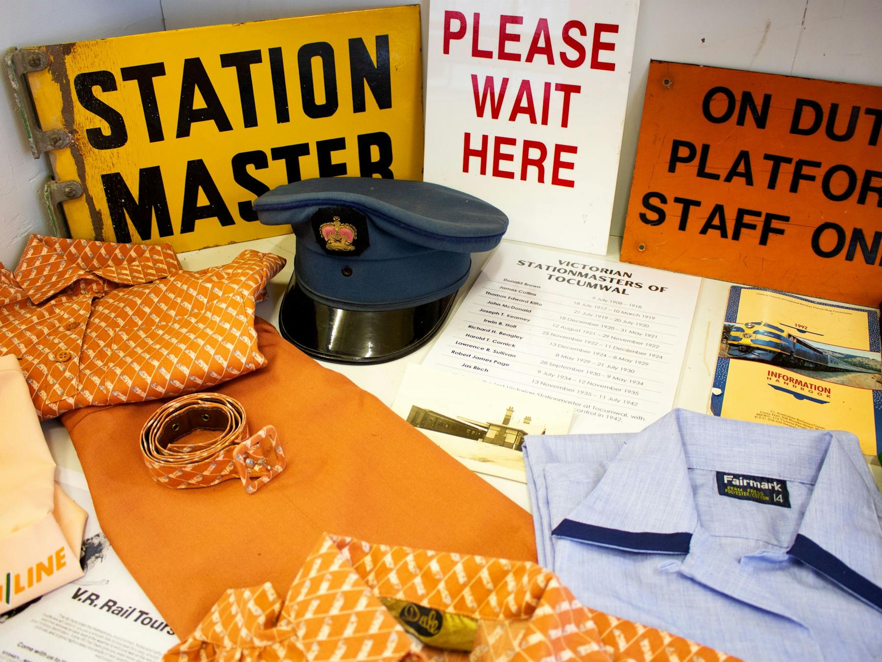 Mueseum cabinet display, featuring a railway uniform and hat, and railway platform signs