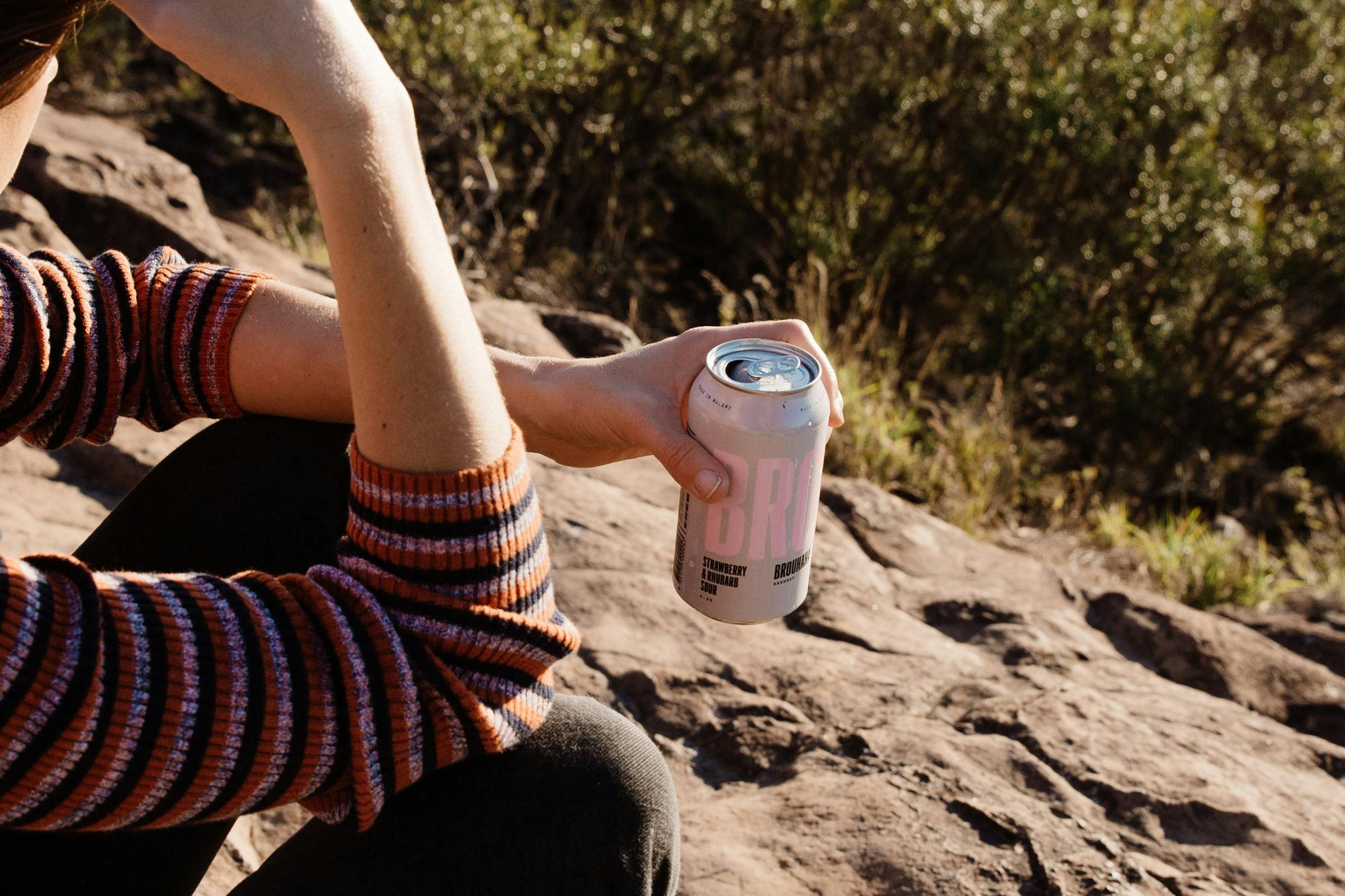 Person holding a can of Brouhaha's Strawberry Rhubarb Sour
