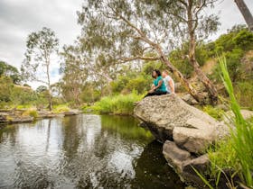 Two people sitting on a rock along side the Barwon River near Buckley Falls