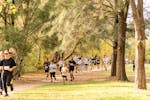 Adults and children running under autumn trees in Tumut