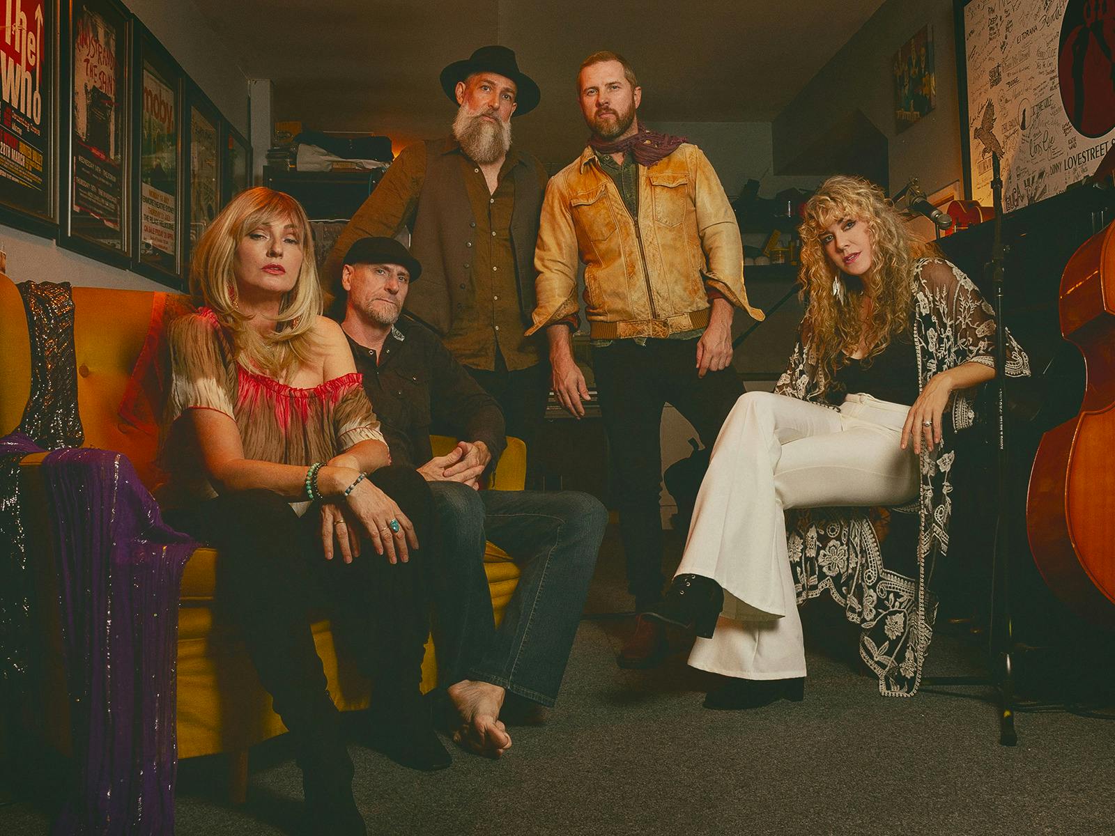 5 band members in a moody studio setting. Looking retro and dressed like Fleetwood Mac